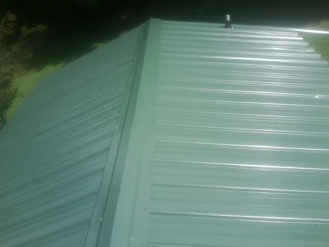 New green metal panels meeting at the ridge of a roof — Flat Roof Repair work by our crew in Missouri Valley
