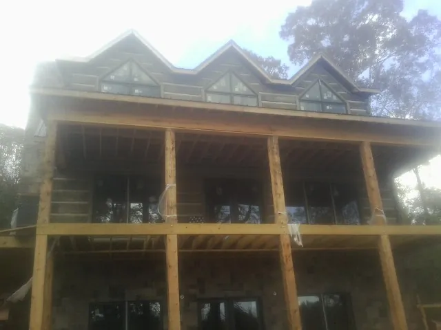 Dormers and porch framing on a large log home under construction — Roof Coating work by our crew in Missouri Valley