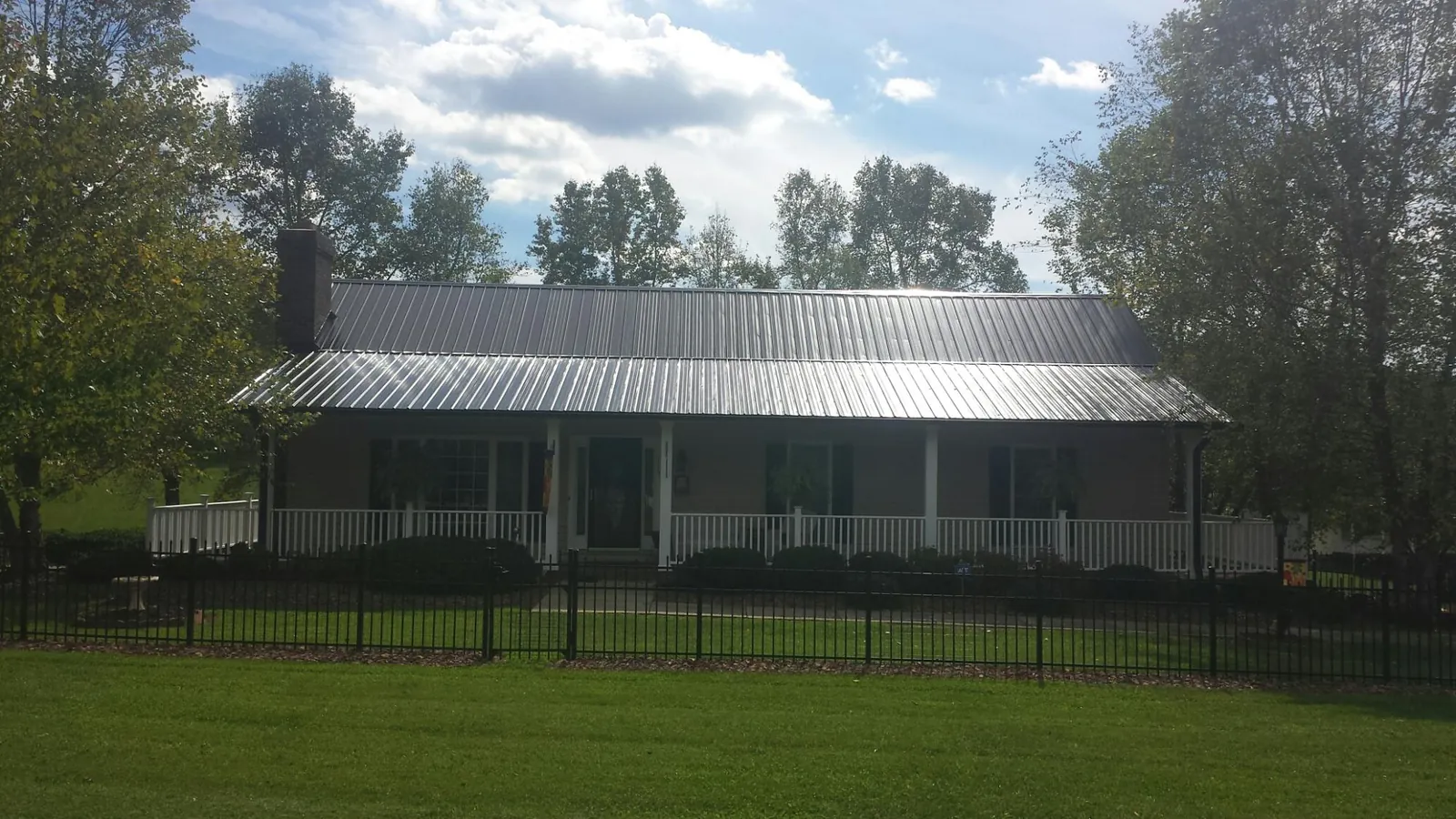 Gray metal roof on a brick ranch with a full width front porch — Gutter Guard Installation work by our crew in Missouri Valley