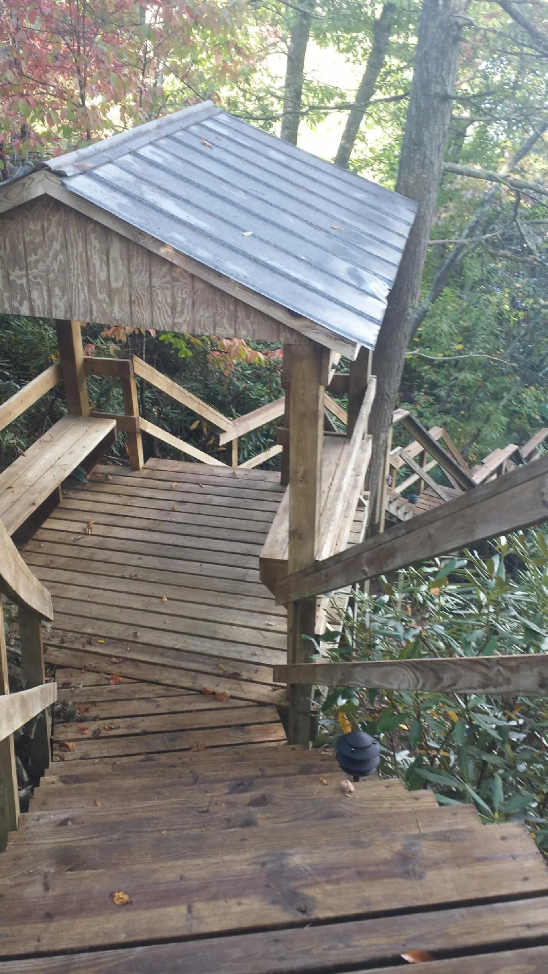Metal roofed shelter over wooden steps on a wooded walkway — Skylight Repair & Installation work by our crew in Missouri Valley