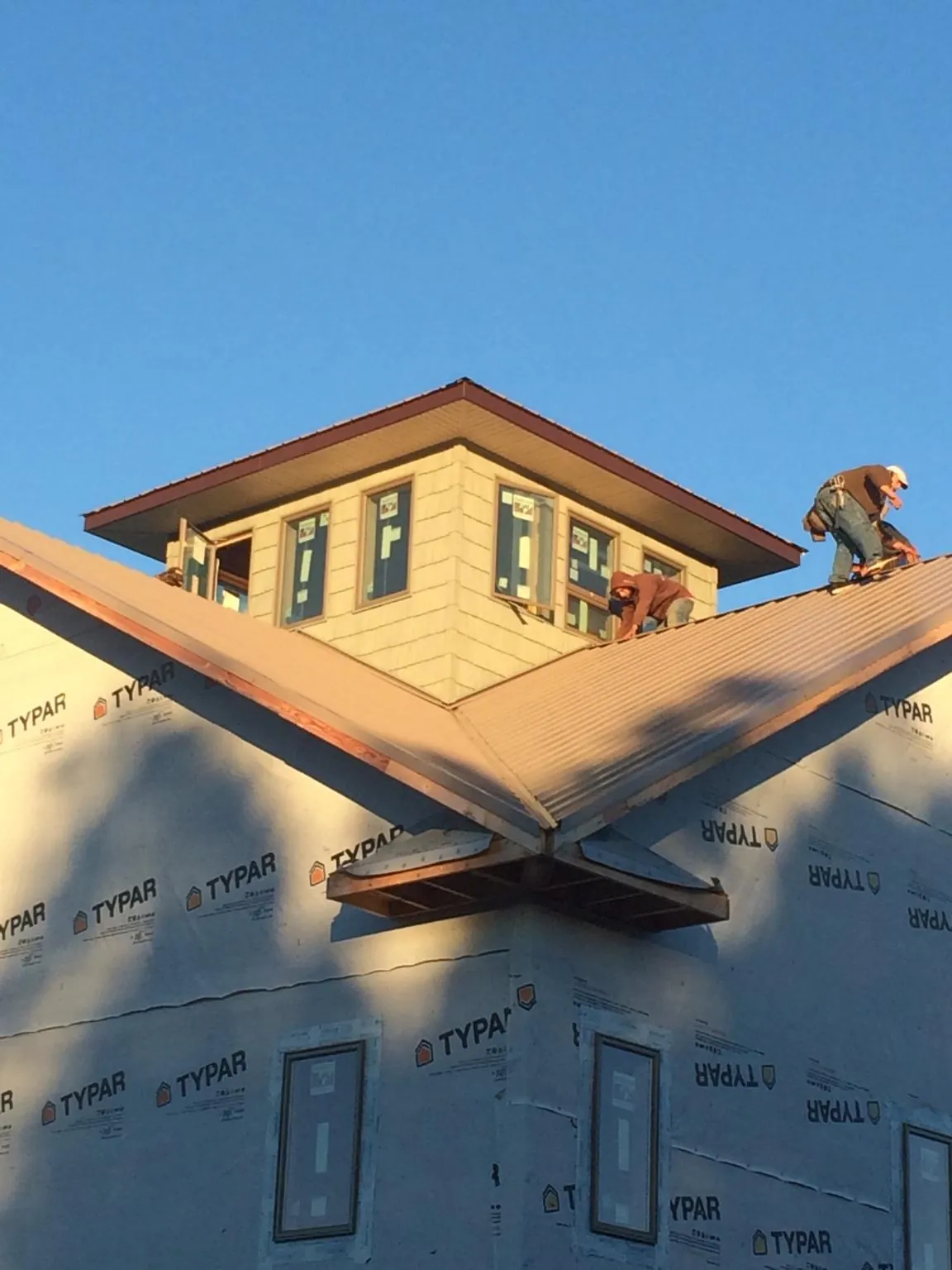 Roofers working around a rooftop cupola on a new metal roof at sunset — Roof Waterproofing in Missouri Valley by Roofing Brothers